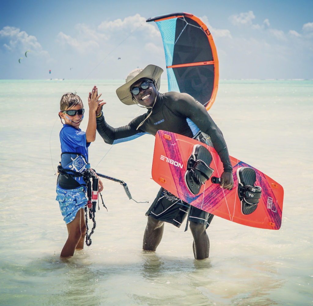 Ben of 9 years old on blue t-shirt from UK is ready for his water start kitesurf lessons with his instructor Baki from Bkite Zanzibar kitesurfing school